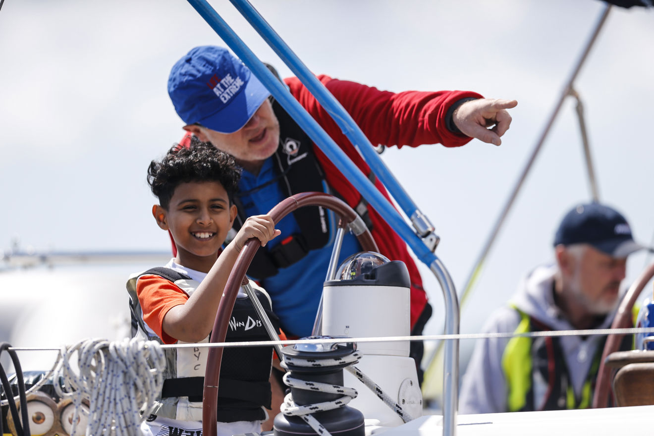 boy on the helm of boat with instructor
