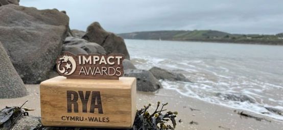 Wooden RYA CW Impact Award on a beach next to the sea.