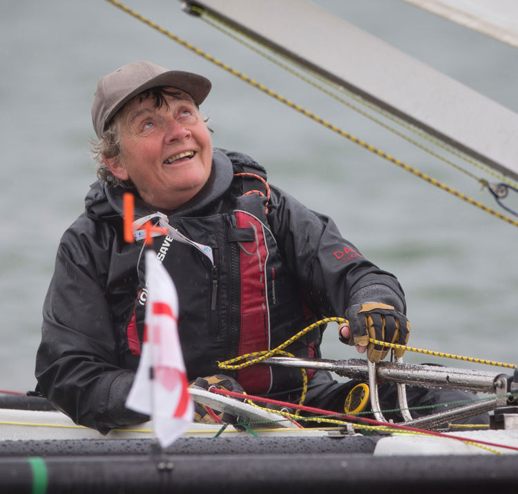 Woman sailing independently, looking up at sail and smiling
