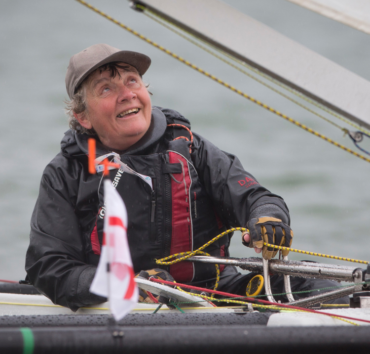 Woman sailing independently, looking up at sail and smiling