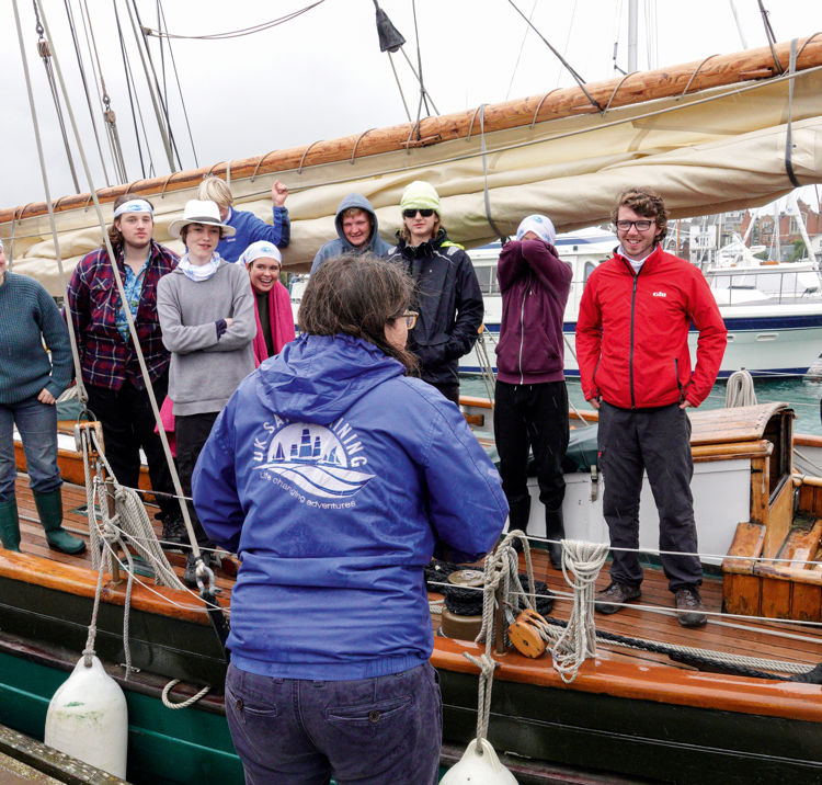 ASTO Lucy Grodie talking to a group of people standing on the side of a yacht in a row