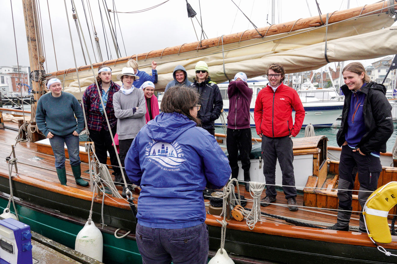ASTO Lucy Grodie talking to a group of people standing on the side of a yacht in a row