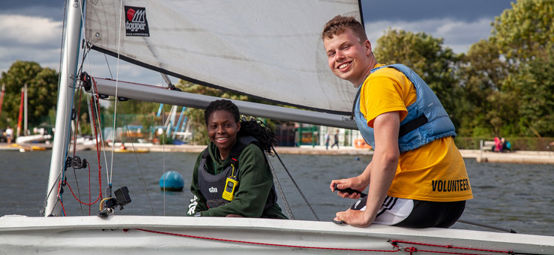 two young sailors smiling at the camera from their boat