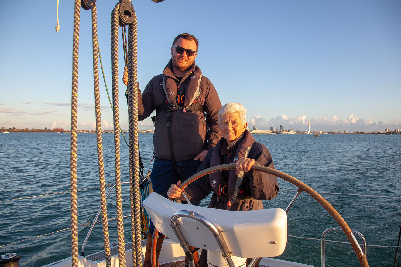 Man and woman sailing a boat at dusk