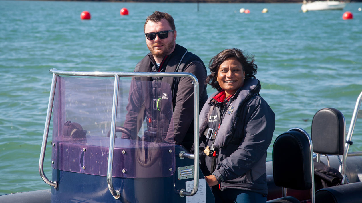 a posed shot of a man and a woman driving a motor boat on a large lake