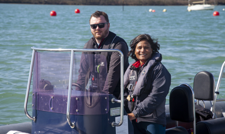 a posed shot of a man and a woman driving a motor boat on a large lake