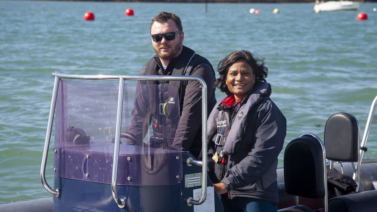 a posed shot of a man and a woman driving a motor boat on a large lake