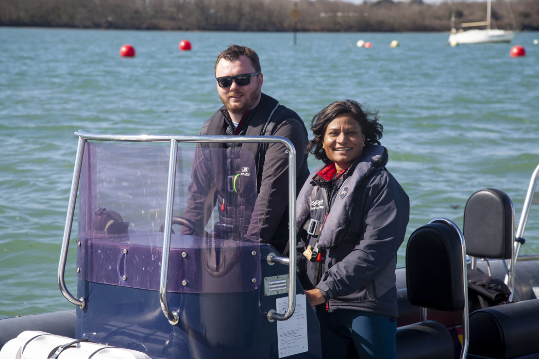 a posed shot of a man and a woman driving a motor boat on a large lake