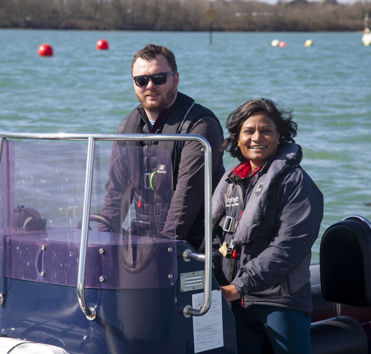 a posed shot of a man and a woman driving a motor boat on a large lake