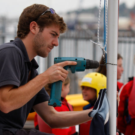 Volunteer holding a drill and fixing their boat