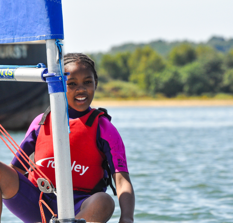 Young sailor smiling as they stand on boat and look out at the distance