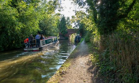 Canal boat on inland waterways sailing towards bridge