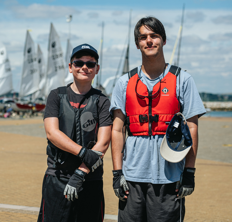 sailors stood on beach with boats in the background