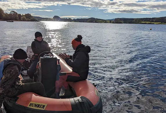 People driving a rigid inflatable boat (RIB) alongside a pontoon