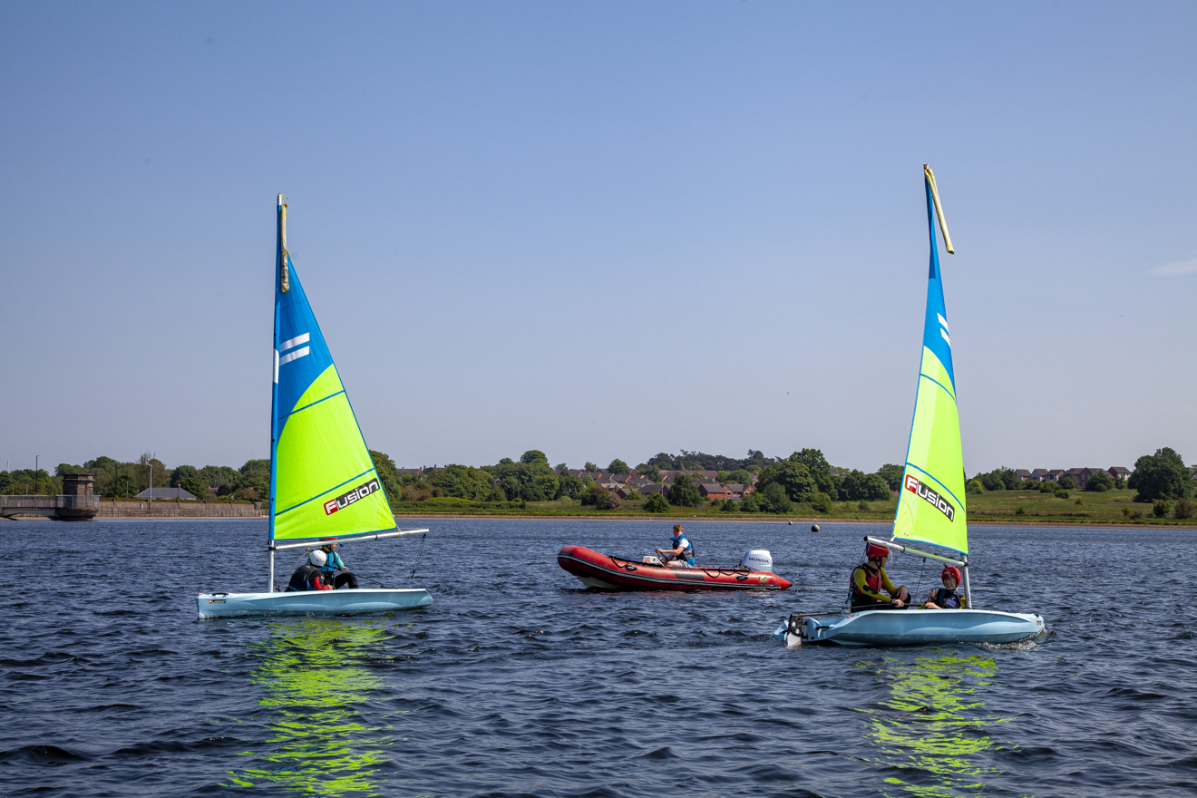 Two dinghies and a powerboat sailing through the water