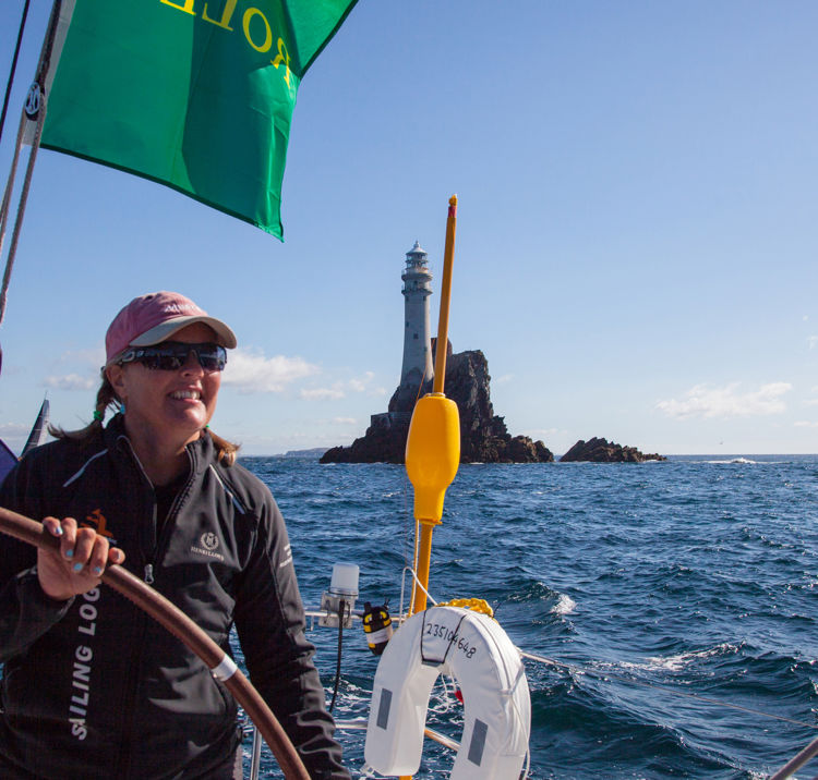 woman steering boat across calm waters with lighthouse in the background