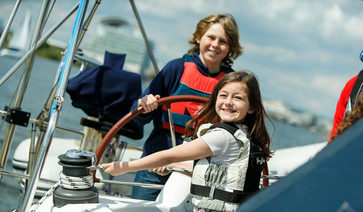 young girl and boy on sailing yacht, the boy is steering and the girl is puling the rope