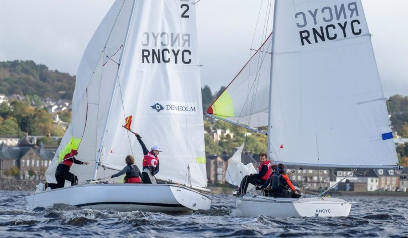 Two teams at the Ceilidh Cup match racing RNCYC Sonar keelboats downwind with spinnakers flying and one team holding up a protest flag.