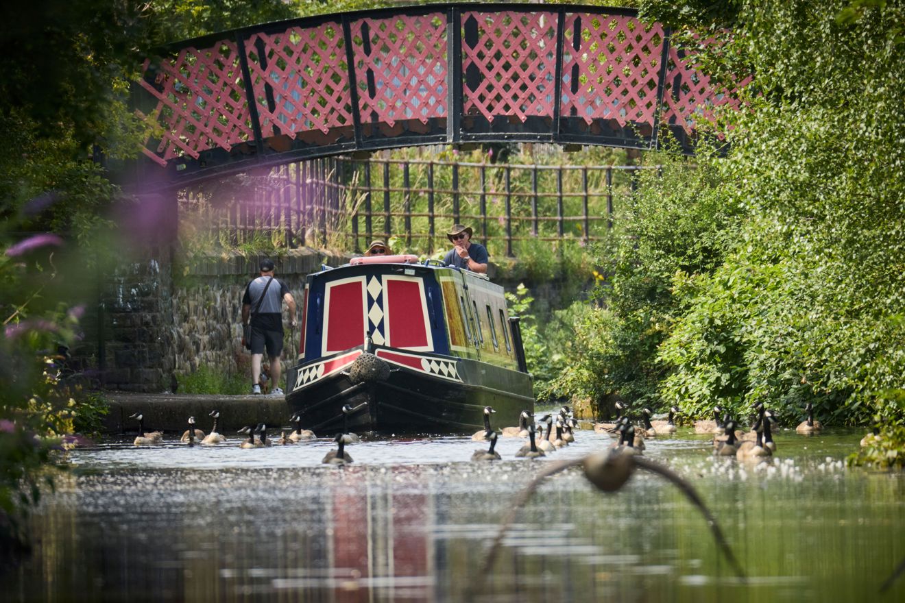 Family operating a narrowboat along a canal