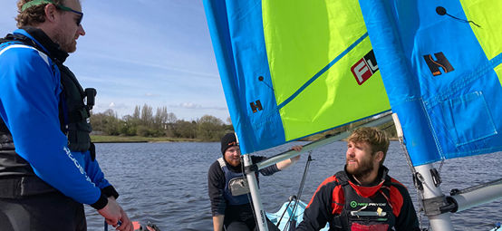 Mid shot of dinghy instructor teaching two older students