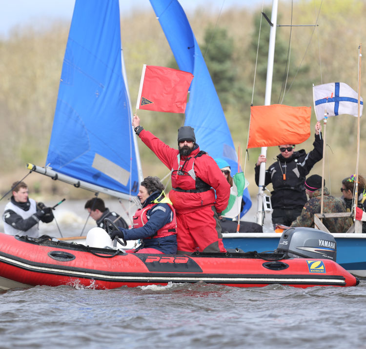 An image of people on a boat with umpire holding a red flag
