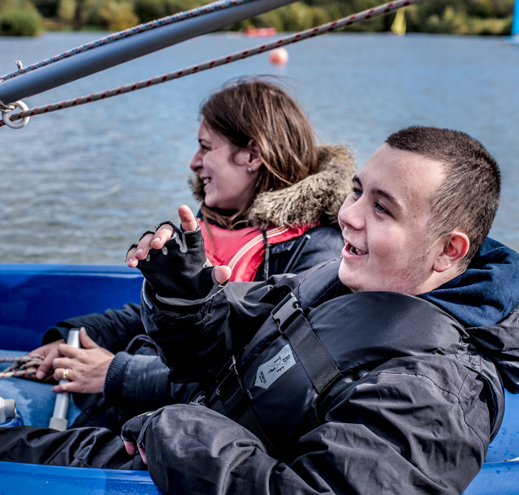 Two adults, smiling and laughing while sailing