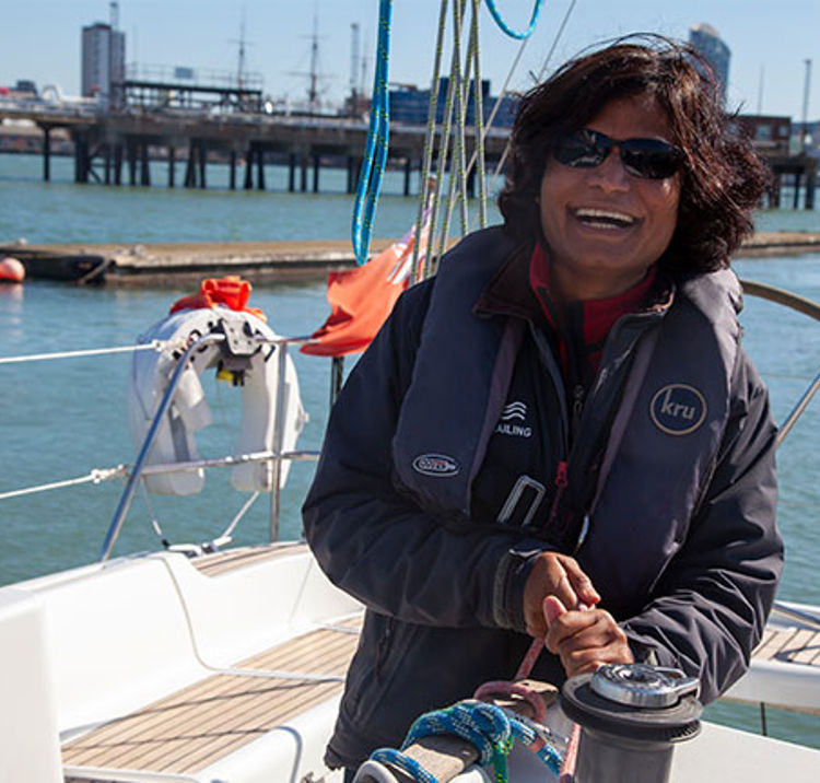 Woman smiling in sailing yacht cockpit winching rope