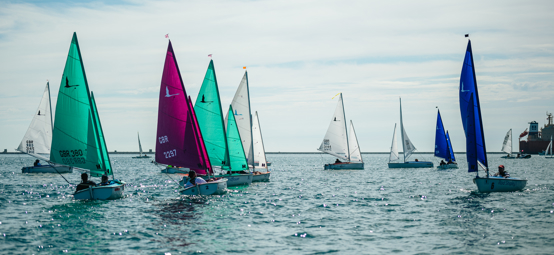 a number of sailing dinghies racing in Portland Harbour on a beautiful sunny day