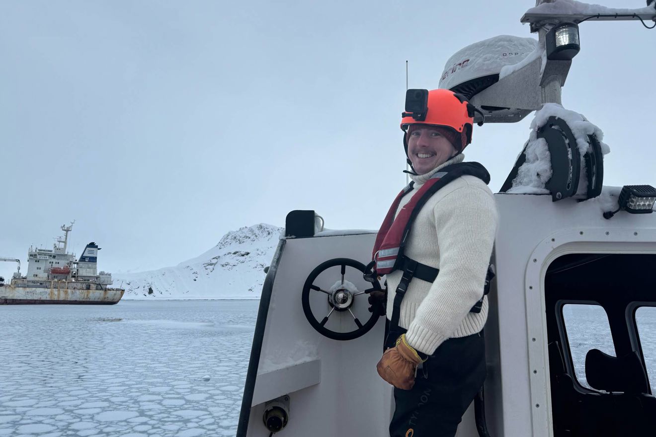 Louis Day on boat in the Antarctic with snowy peaks in background