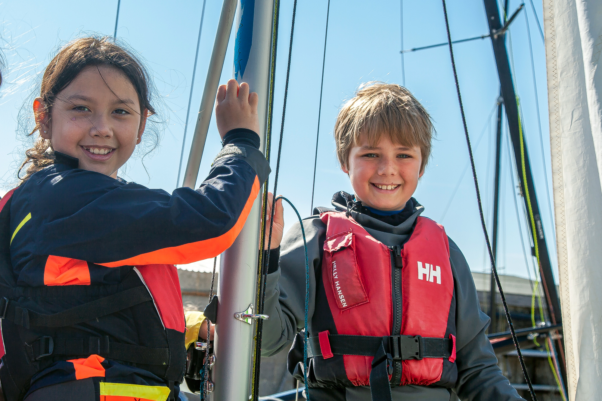 two children holding boat mast and smiling