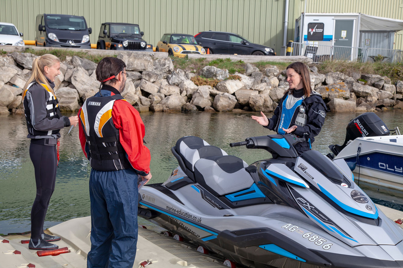 Instructor stood next to jetski explaining safety
