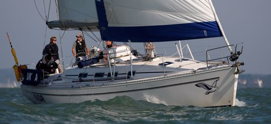 Mid shot of yacht sailing with crew onboard