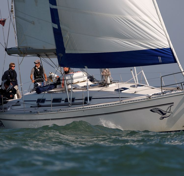 Mid shot of yacht sailing with crew onboard