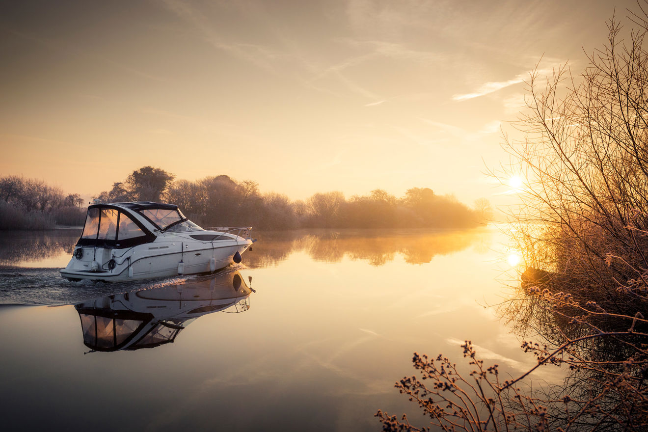 Power boat sailing through a river at sunrise 