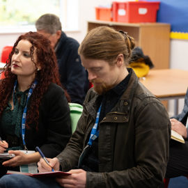 Midshot image of attendees taking notes