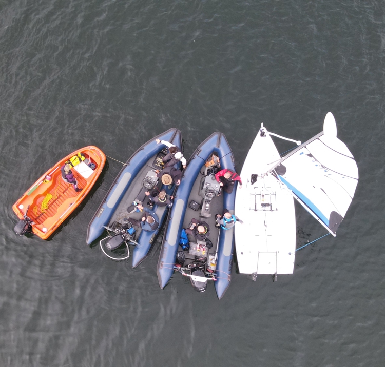 A birds eye view of a keelboat (sailing vessel) and three rescue craft alongside each other, on the water, ready for testing recovery techniques