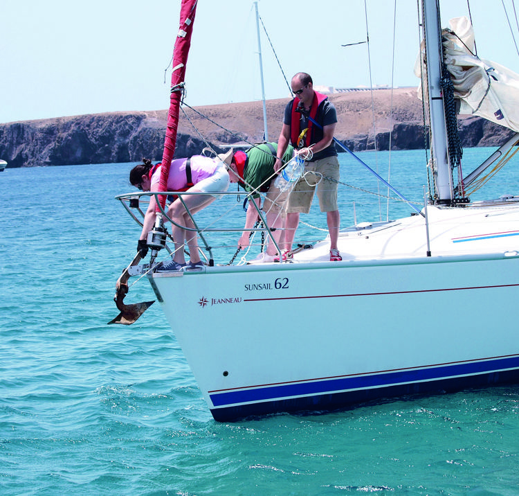 Wide shot of crew on a yacht anchoring with care