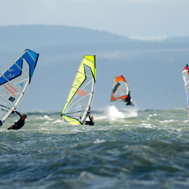 group of windsurfers on the ocean in the distance
