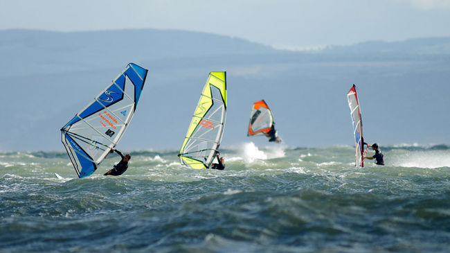 group of windsurfers on the ocean in the distance