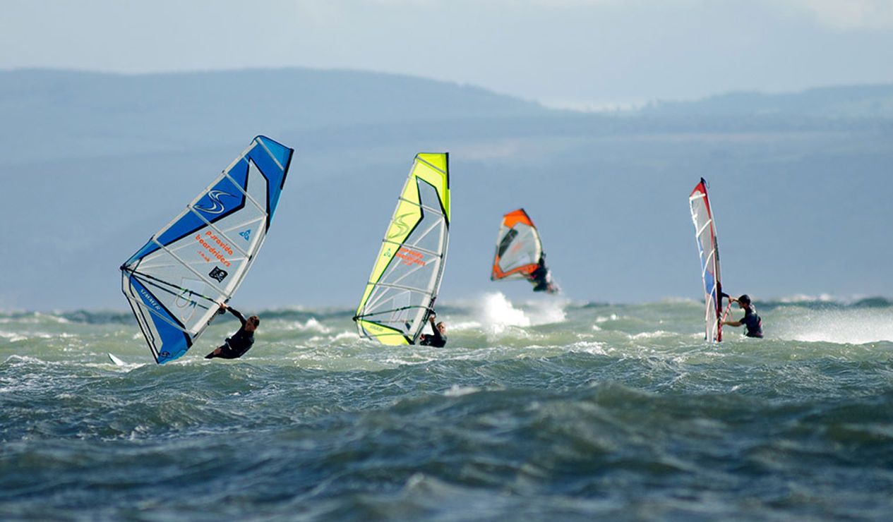 group of windsurfers on the ocean in the distance
