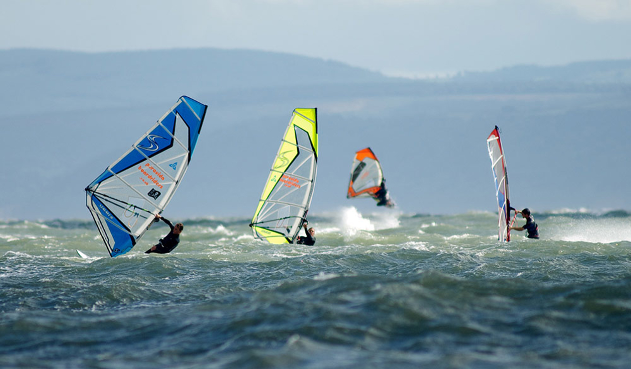 group of windsurfers on the ocean in the distance