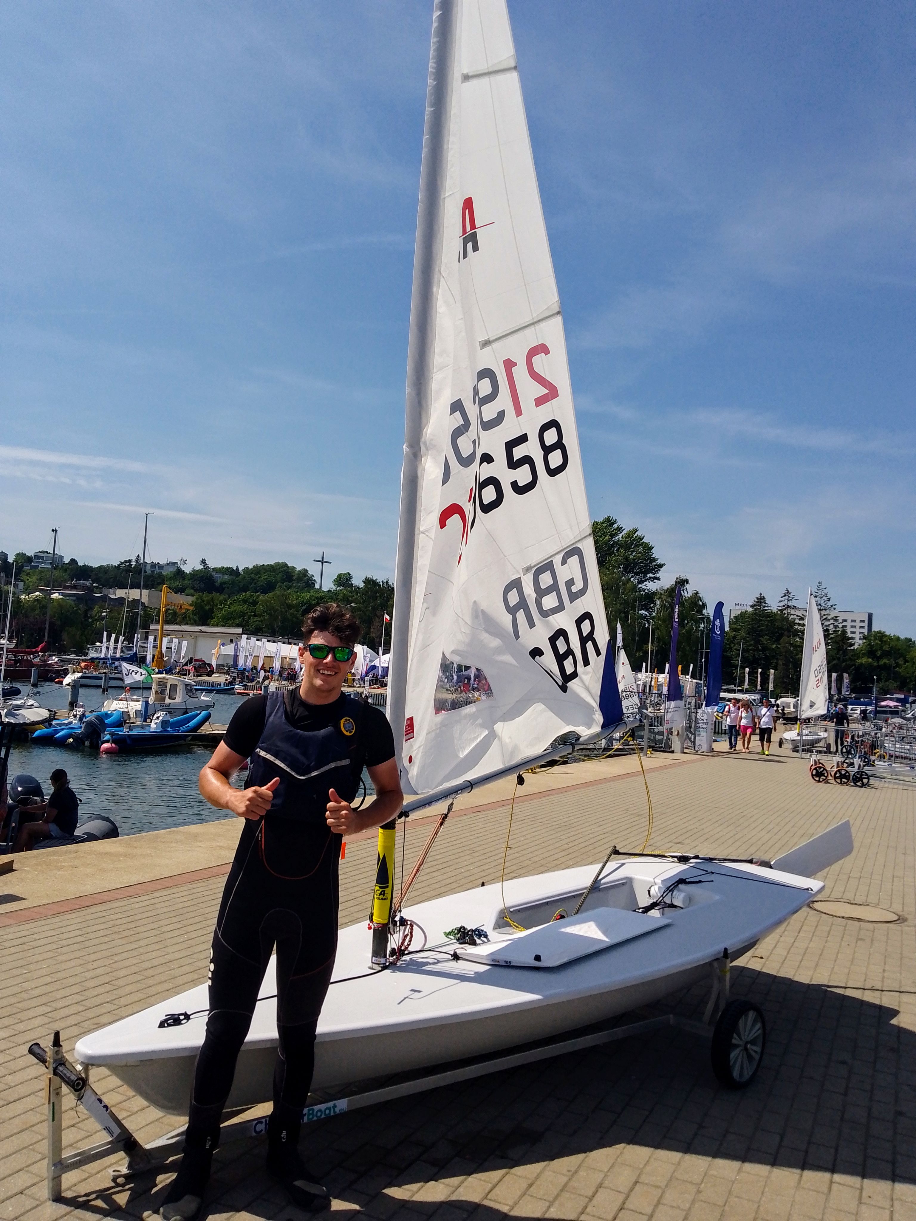 will dylson standing in front of a dinghy with his thumbs up