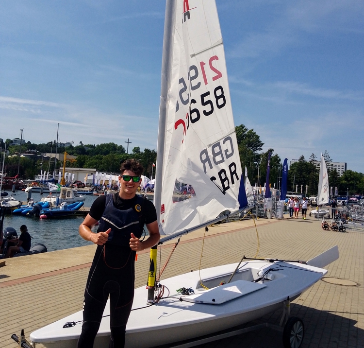 will dylson standing in front of a dinghy with his thumbs up