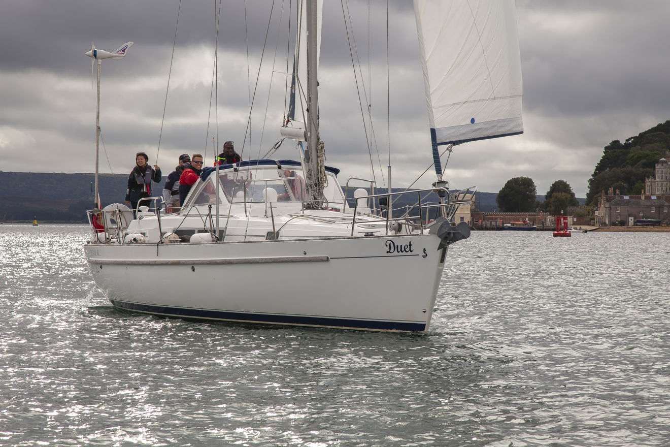 4 people sailing a boat on the coast.