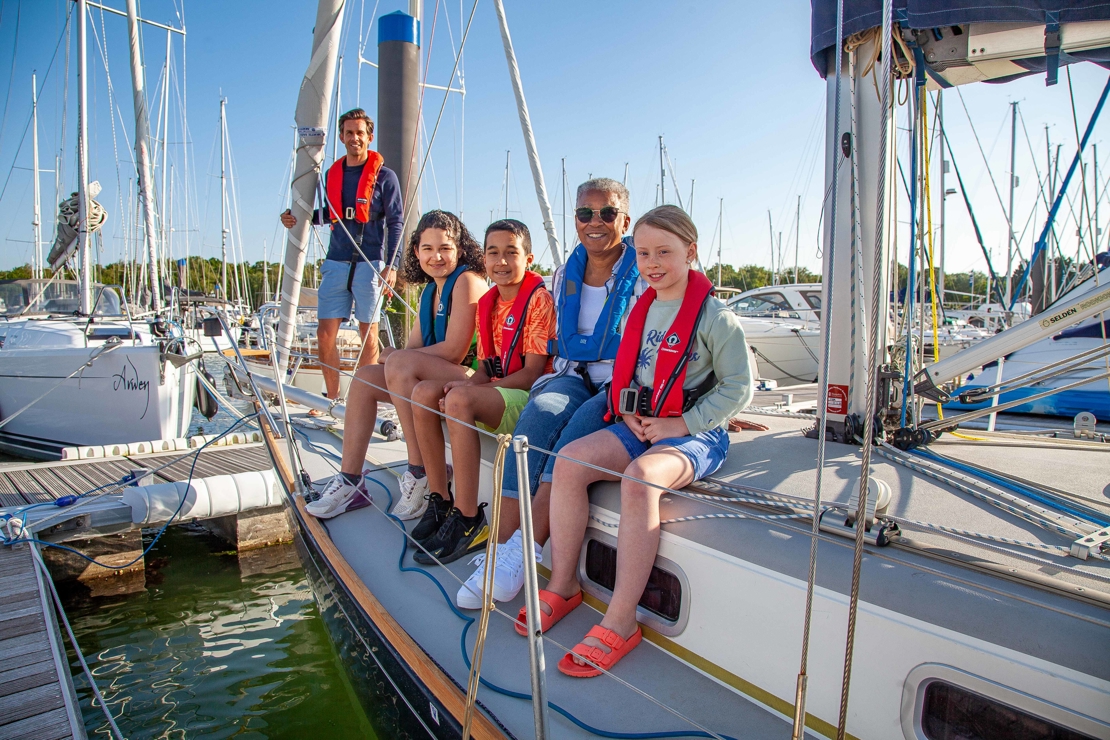 Smiling family sat on the edge of their boat