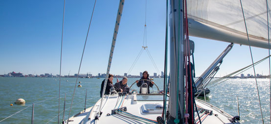 3 people sailing a boat on the open water