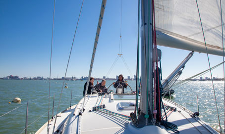 3 people sailing a boat on the open water
