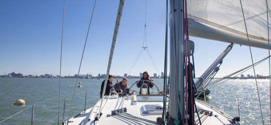3 people sailing a boat on the open water