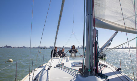 3 people sailing a boat on the open water