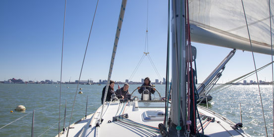 3 people sailing a boat on the open water